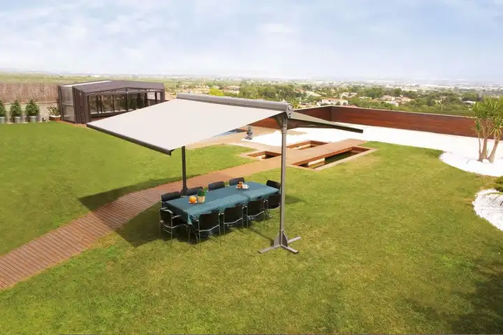 Abri de terrasse à toile claire vu d’en haut, ses deux pentes ombrageant une grande table de jardin