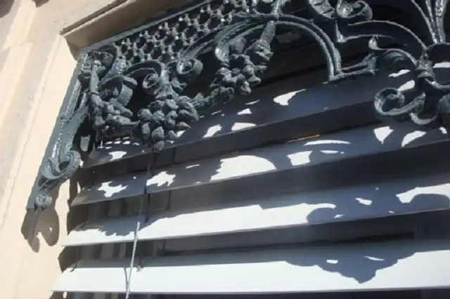 Cantonnière en fonte ouvragée et, dessous, les lames d’un brise-soleil, sur une façade lyonnaise
