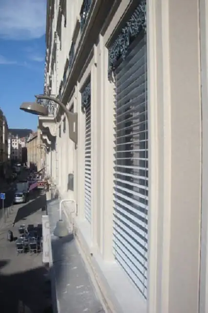 Fenêtres d’un immeuble lyonnais équipées de lames orientables, au-dessus d’une rue
