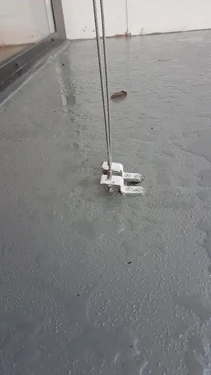 Câble inox de guidage fixé au sol, au pied d’une baie