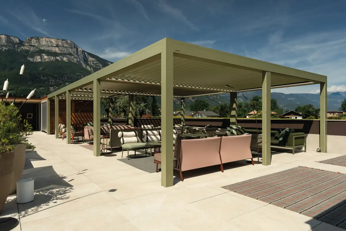 Grande pergola à lames vert olive couvrant la terrasse d’un toit, face aux montagnes