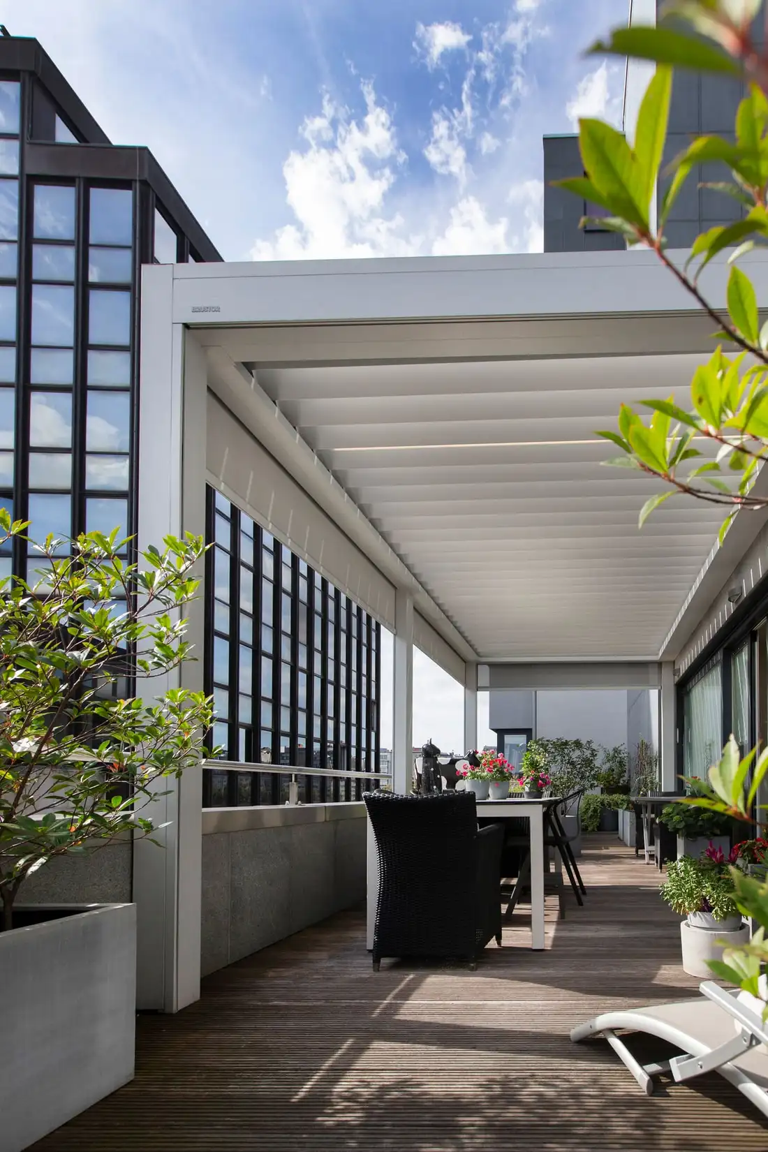 Pergola à lames blanches sur la terrasse d’un appartement, entre deux immeubles