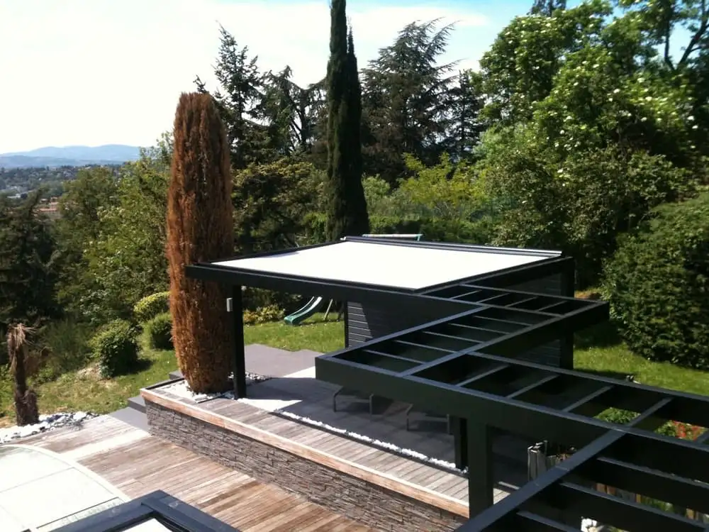Pergola noire à toiles blanches au-dessus d’une terrasse en bois, face aux collines