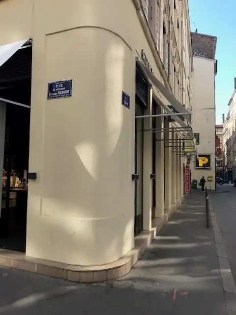 L’angle arrondi de l’immeuble et la file de bannettes le long de la rue
