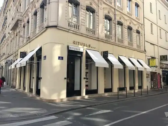Angle d’un immeuble ancien de Lyon, avec les bannettes blanches de la boutique Rituals