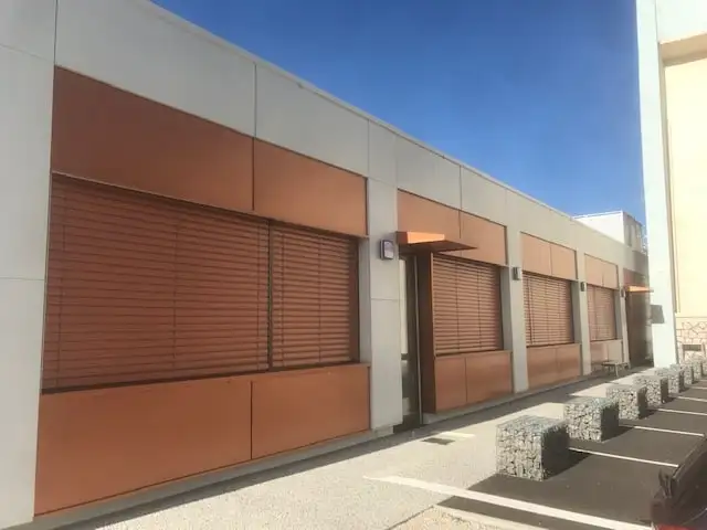 Bâtiment RTE : brise-soleil orientables couleur cuivre baissés devant les fenêtres
