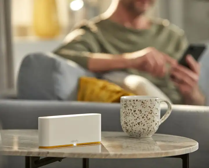 Box domotique Somfy TaHoma switch posée sur une table basse, devant un canapé