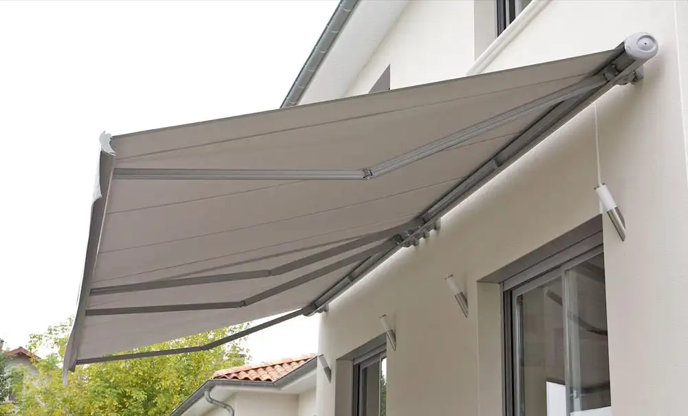 Store banne gris à coffre déployé contre une façade blanche