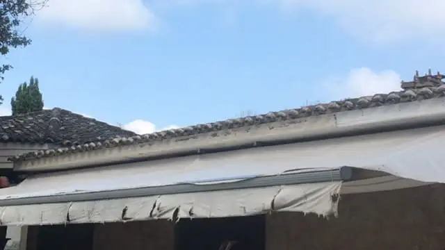 L’ancienne toile du store, usée et déchirée, avant son remplacement