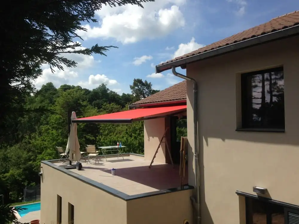 Store banne à toile rouge déployé au-dessus d’un toit-terrasse, à Saint-Didier-au-Mont-d’Or