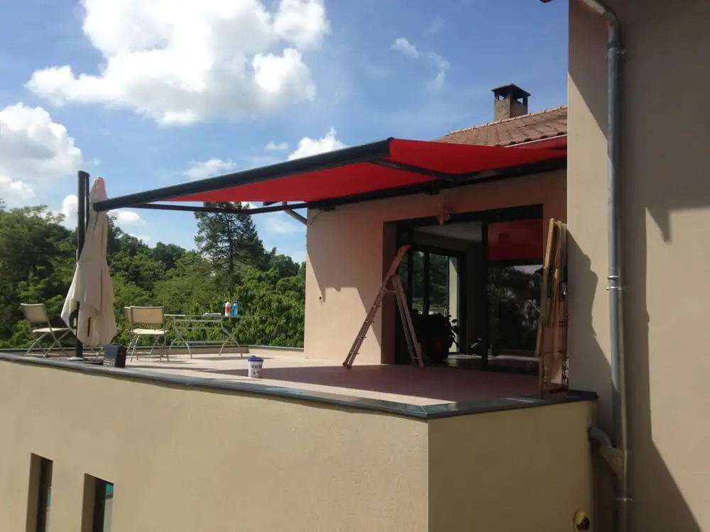 Store banne rouge déployé sur toute la largeur d’un toit-terrasse, au-dessus du salon de jardin, à Saint-Didier-au-Mont-d’Or