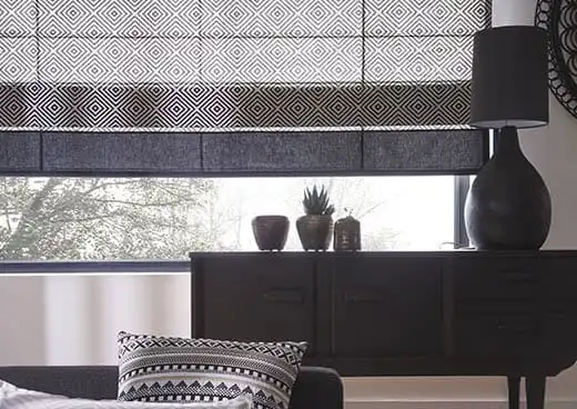 Store bateau à motifs géométriques noirs et blancs, relevé au-dessus d’une commode