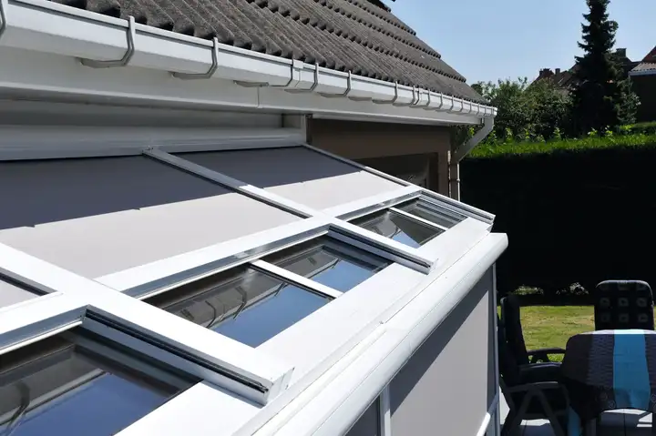 Stores extérieurs tendus sur les fenêtres de toit d’une véranda blanche