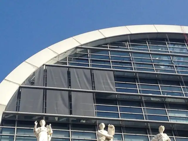 Stores enrouleurs extérieurs gris baissés sur la façade vitrée de l’Opéra, au-dessus des statues