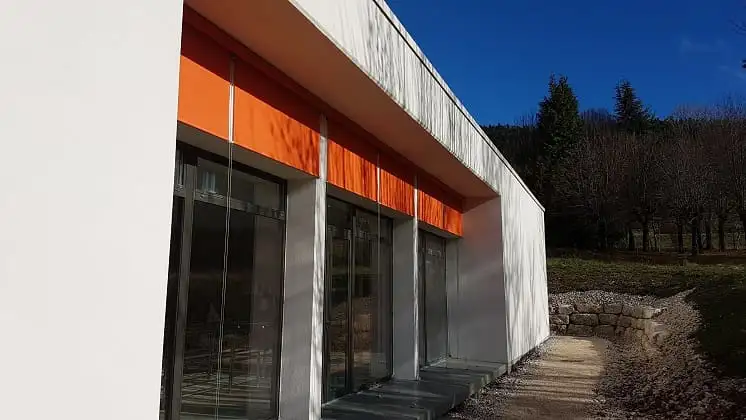 Stores enrouleurs orange à demi baissés devant les grandes baies vitrées
