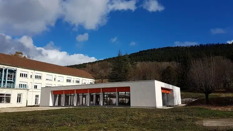 Vue d’ensemble du bâtiment et de ses stores orange, devant l’hôpital